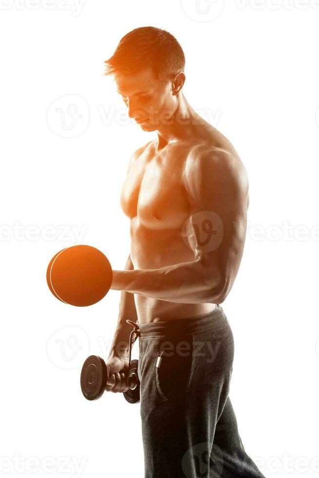 Athletic man showing muscular body and doing exercises with dumbbells photo