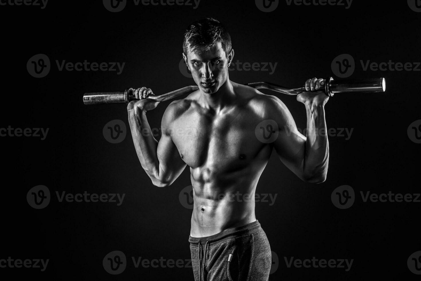 Strong man holding barbell on his shoulders, looking at camera photo