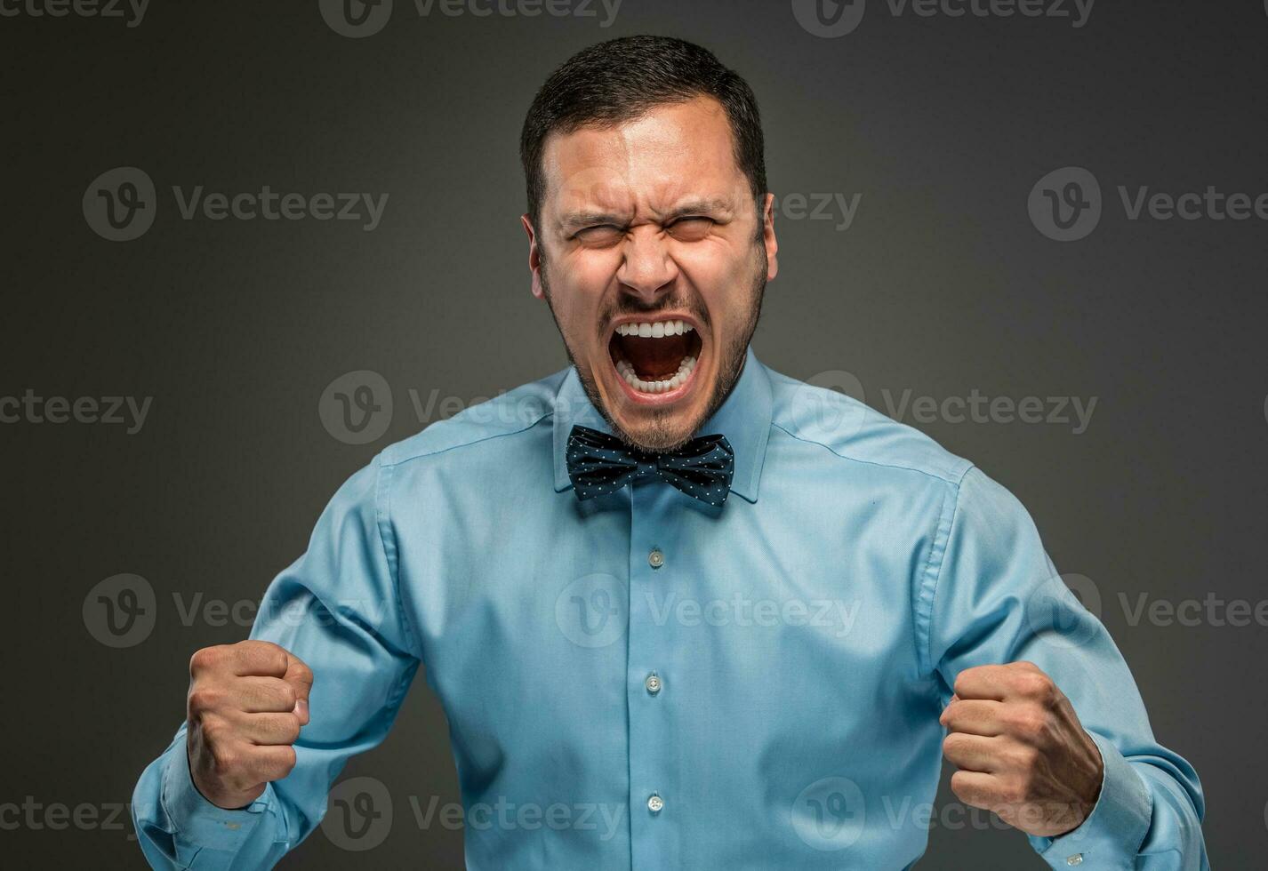 Portrait angry upset young man in blue shirt, butterfly tie photo
