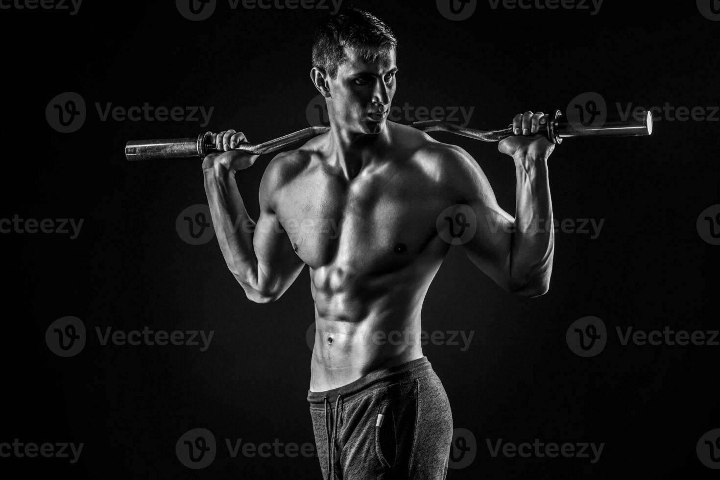 Strong man holding barbell on his shoulders, looking to side photo