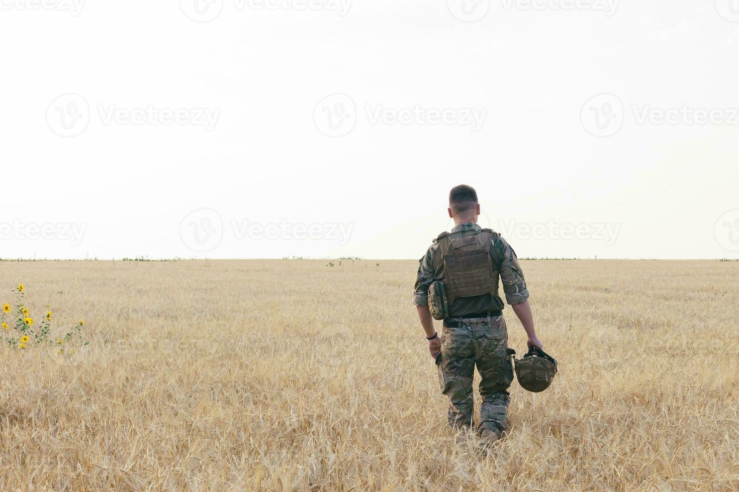 Soldier man standing against a field photo