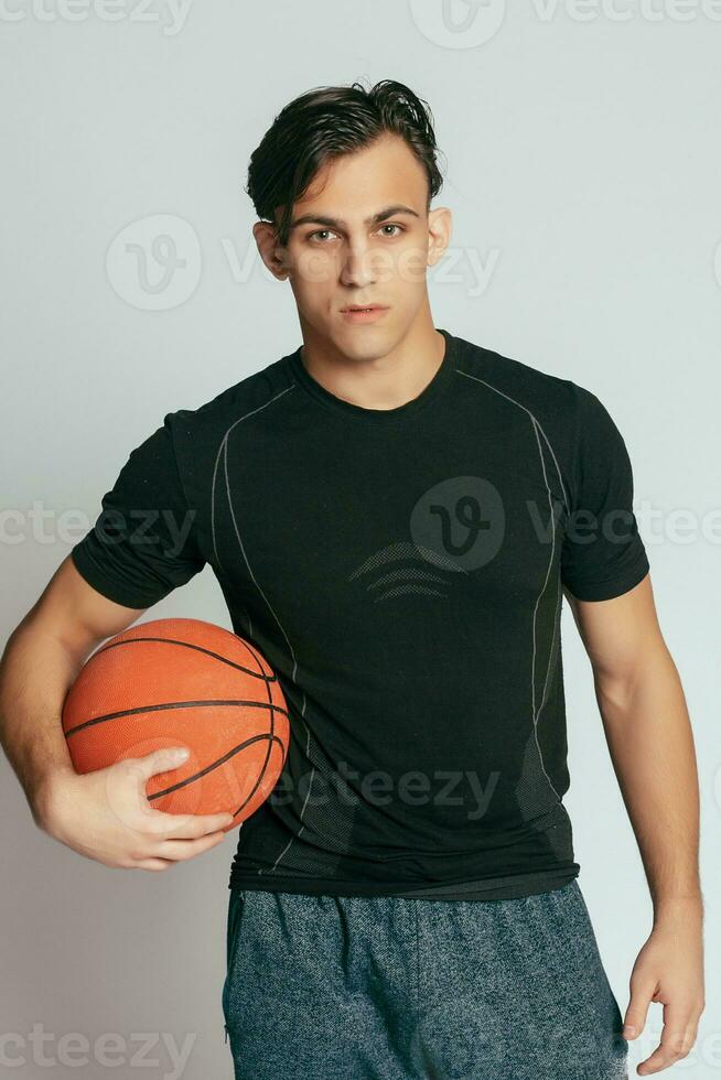 Handsome young smiling man carrying a basketball ball photo