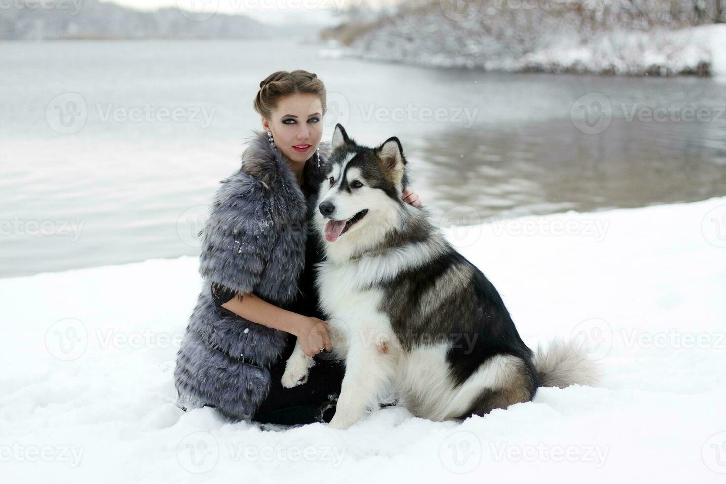 Young woman with wolf dog in snow photo