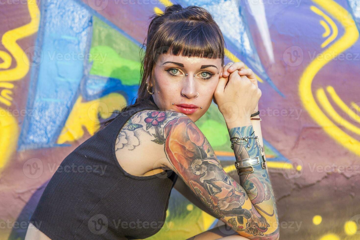 tatuado rebelde niña posando en contra un pared pintado foto