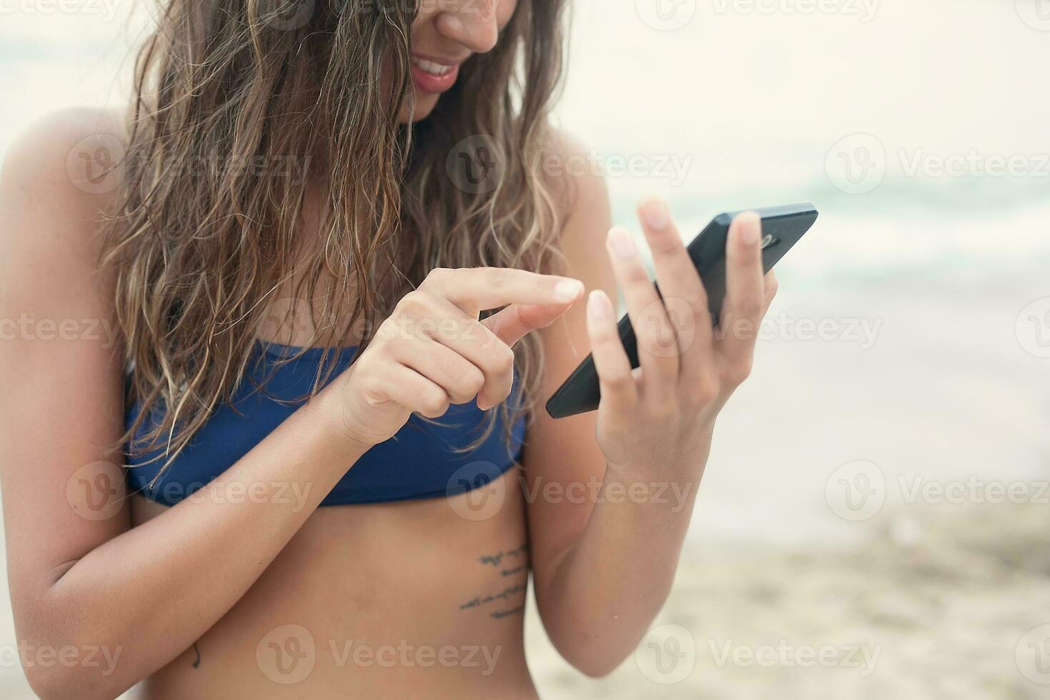 girl with phone on the beach photo