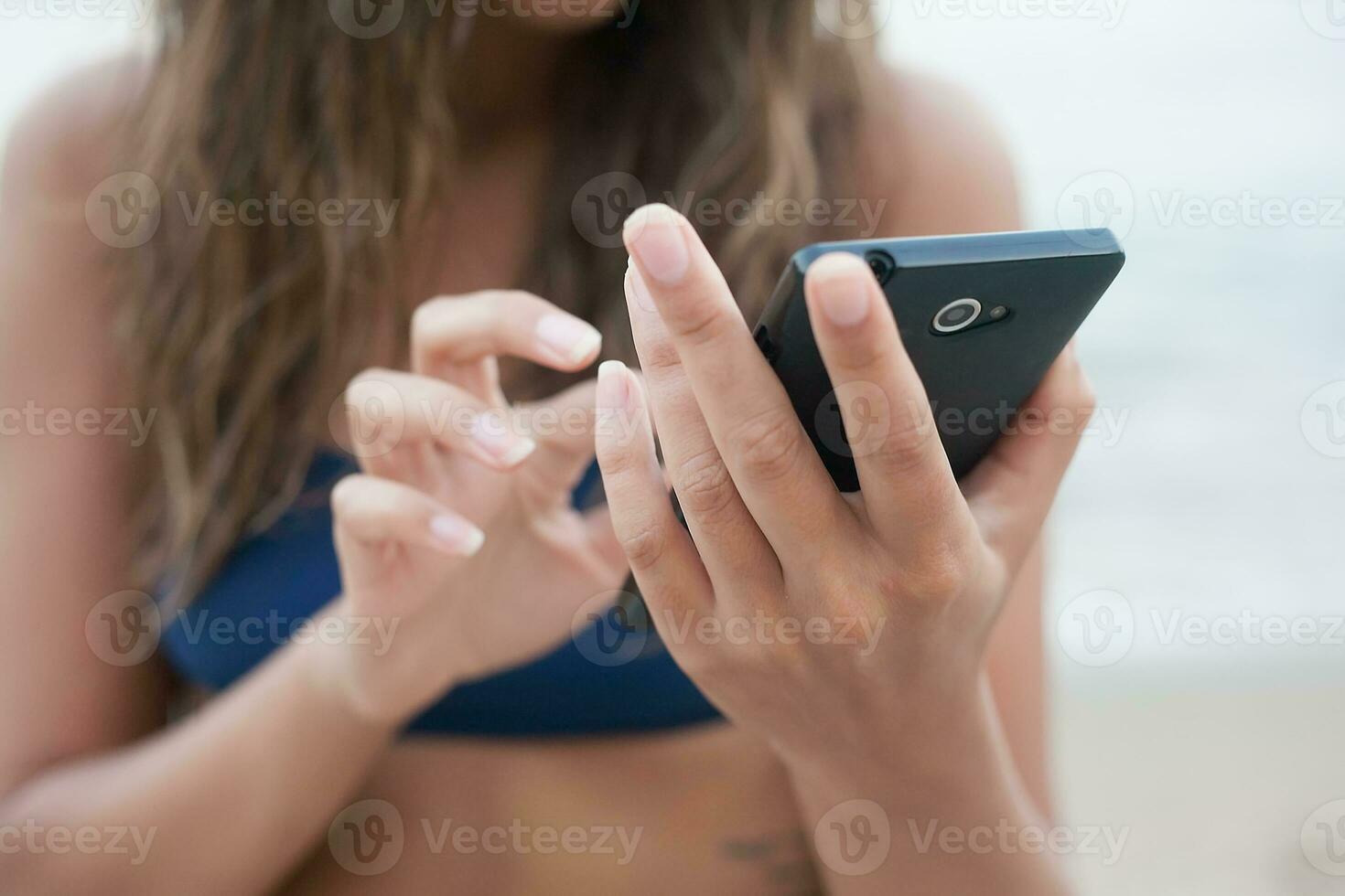 girl with phone on the beach photo