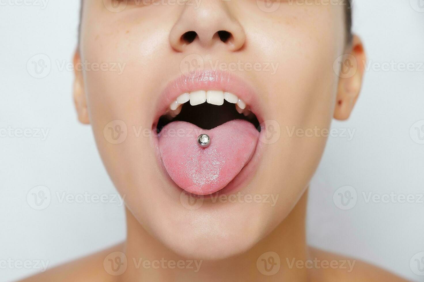Beautiful woman sticking out her tongue and showing young piercing photo