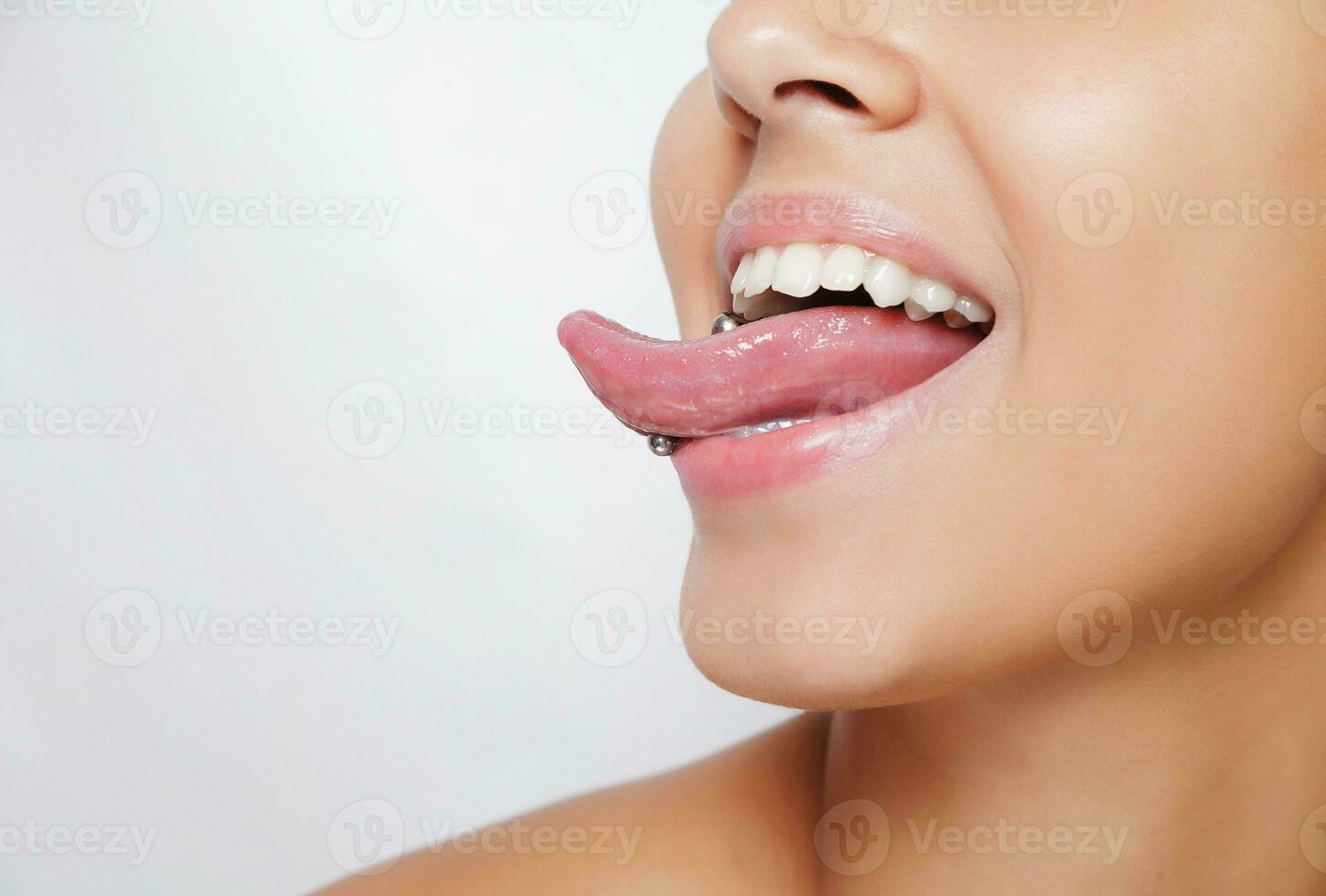 Beautiful woman sticking out her tongue and showing young piercing photo