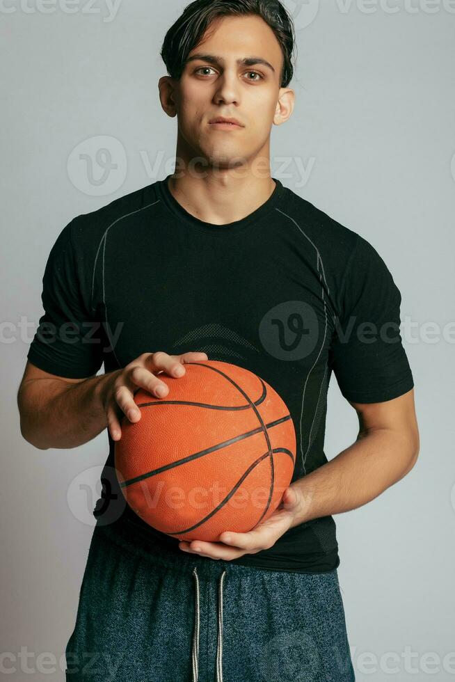 Handsome young smiling man carrying a basketball ball photo