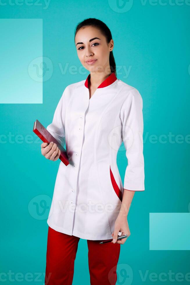 Beautiful woman doctor holding red trousers on turquoise background photo