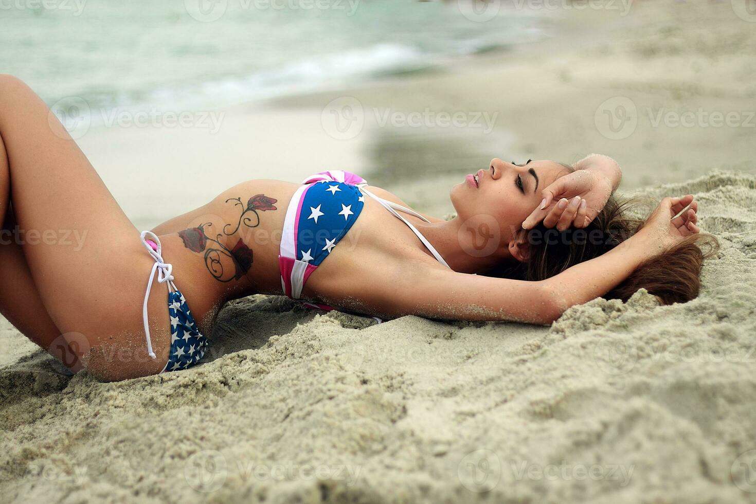 Attractive girl lying on the sand by sea. Sunny day. photo