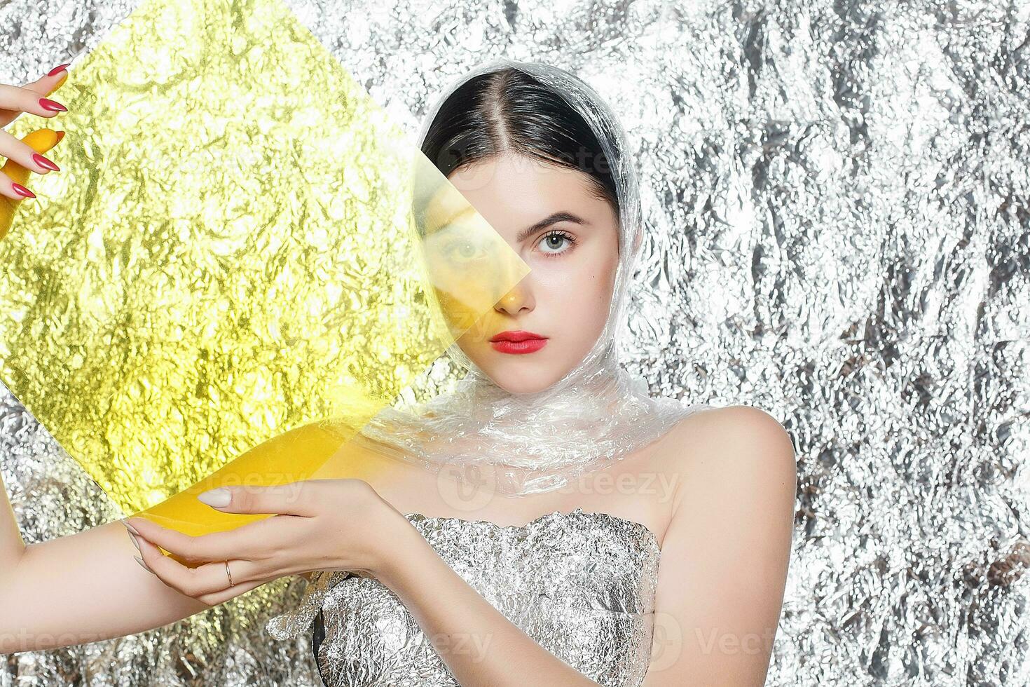 Young beautiful girl in a black dress on a silver background. photo