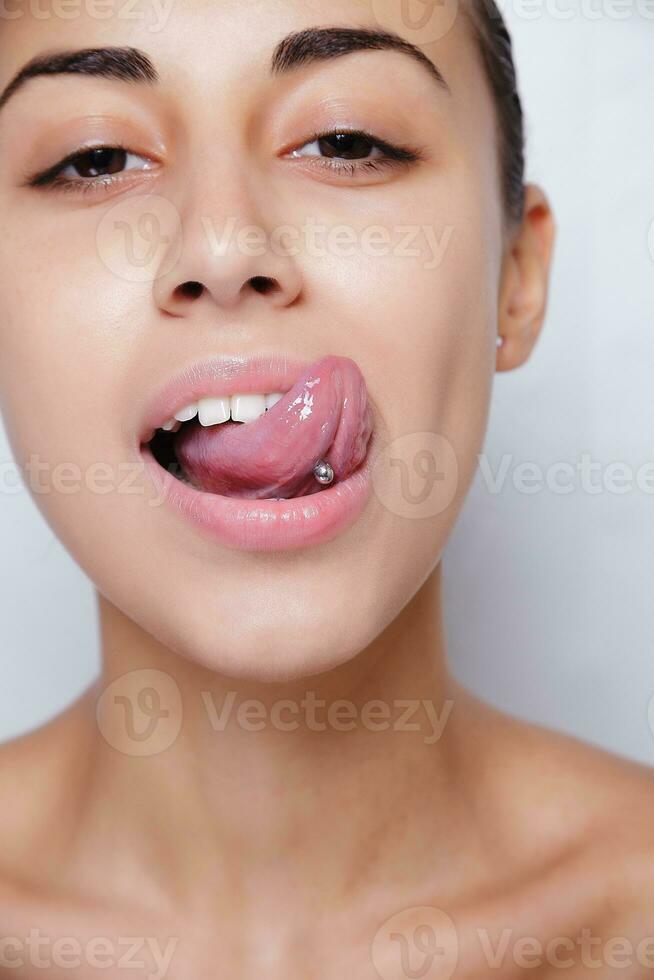 hermosa mujer sacando la lengua y mostrando piercing joven foto