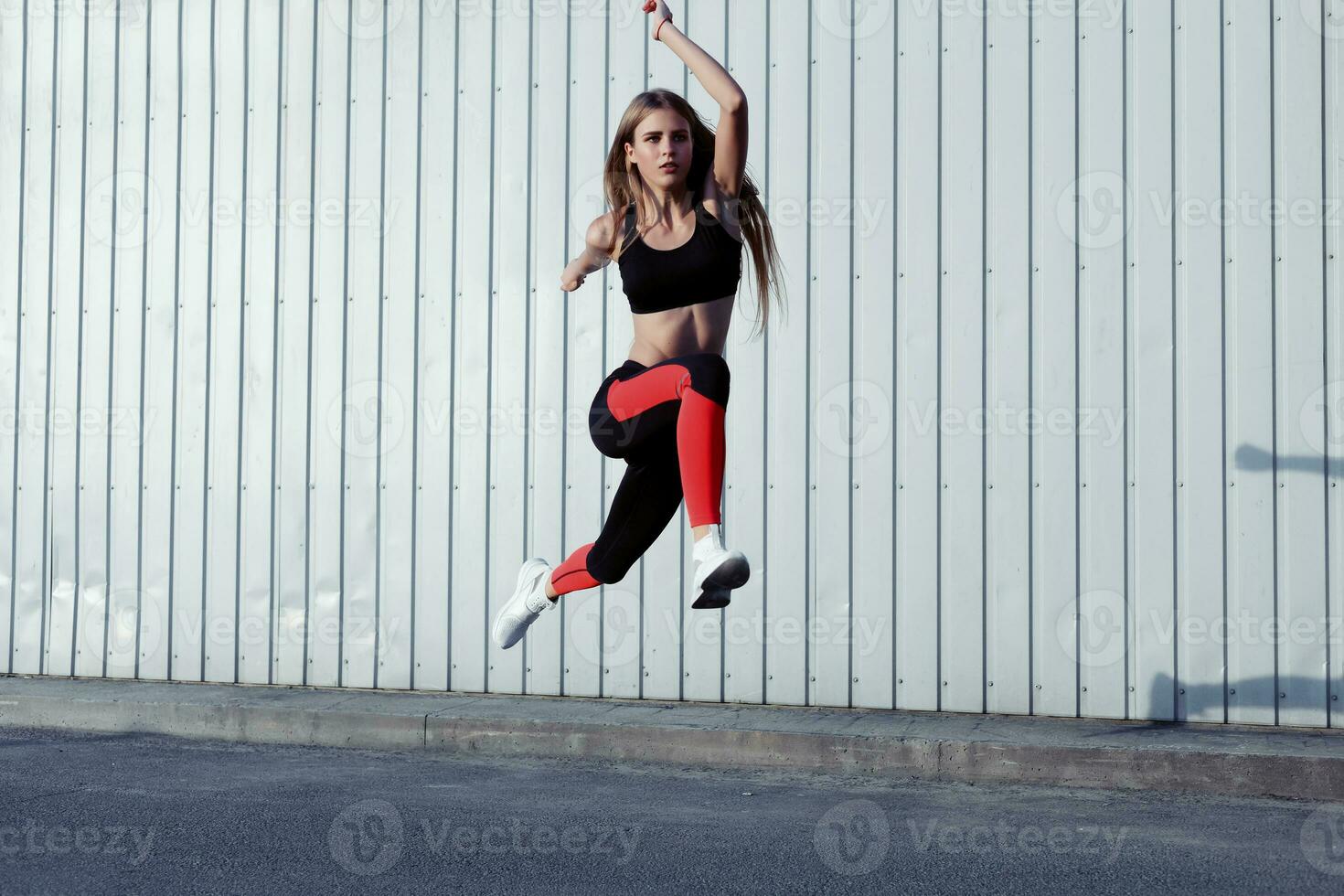 Full length of healthy female exercising and jumping outdoors. photo