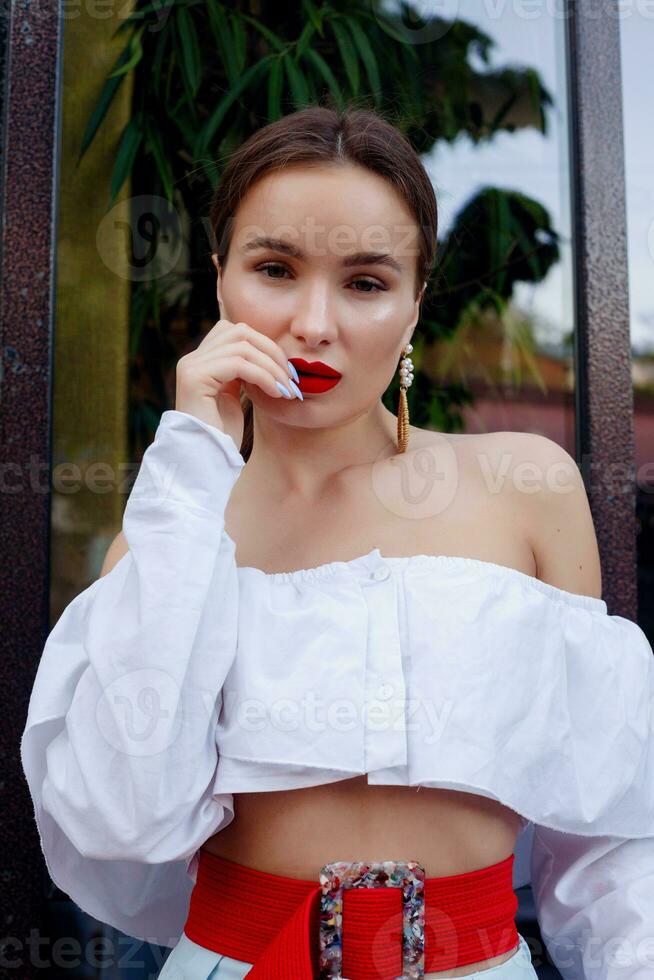 morena vistiendo blanco camisa y azul pantalones. foto