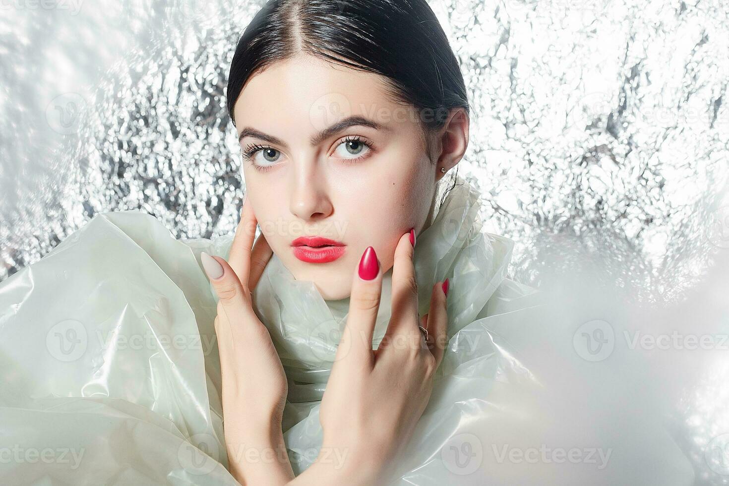 Young beautiful girl in a black dress on a silver background. photo