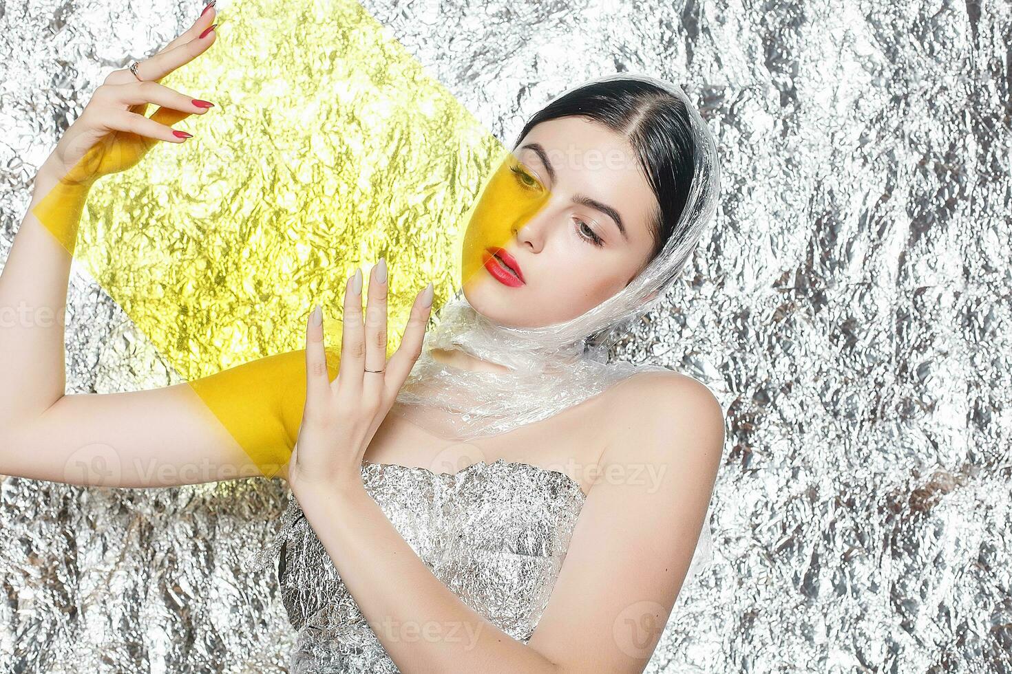 Young beautiful girl in a black dress on a silver background. photo