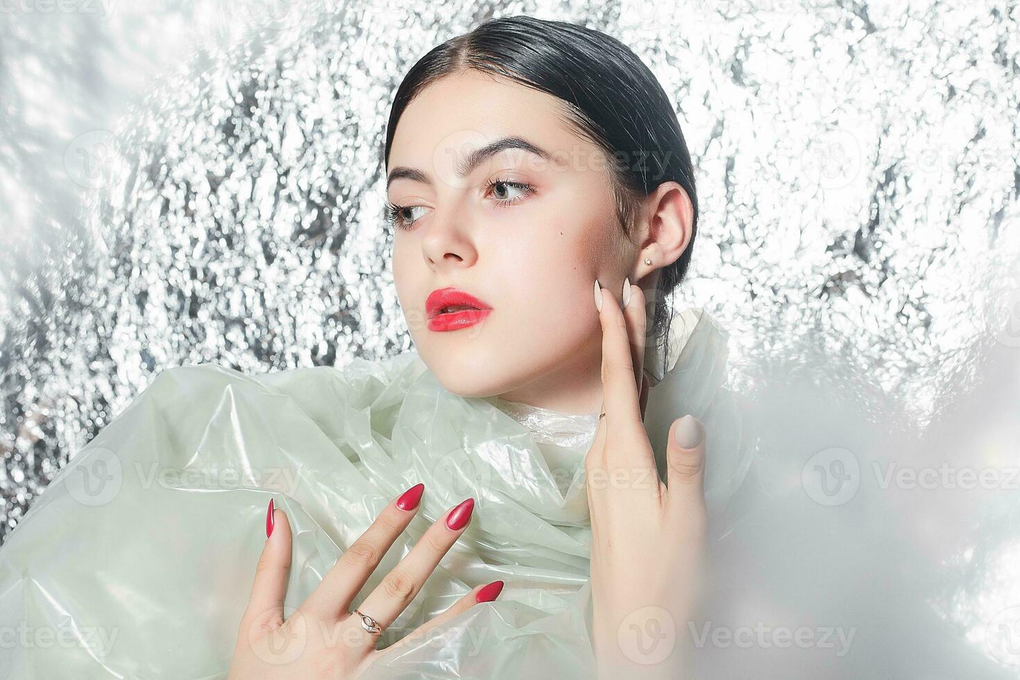 Young beautiful girl in a black dress on a silver background. photo