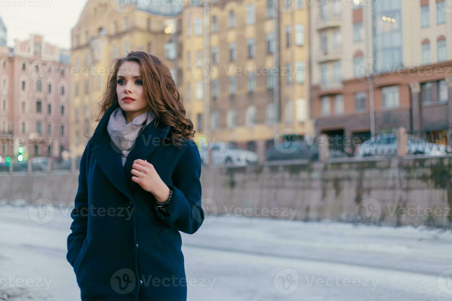 Enthusiastic smiling girl with shiny curls posing in the city photo