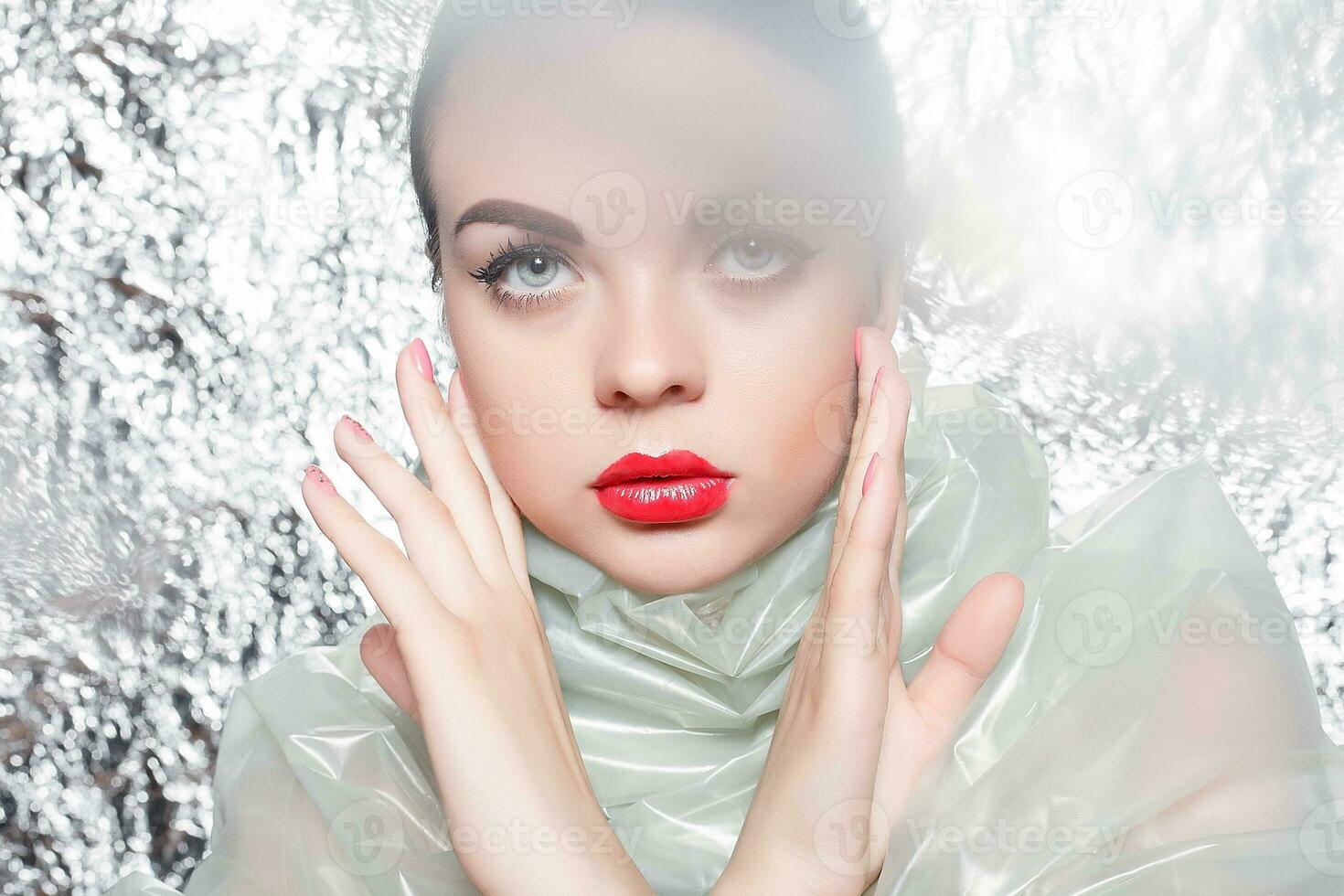 Young beautiful girl in a black dress on a silver background. photo