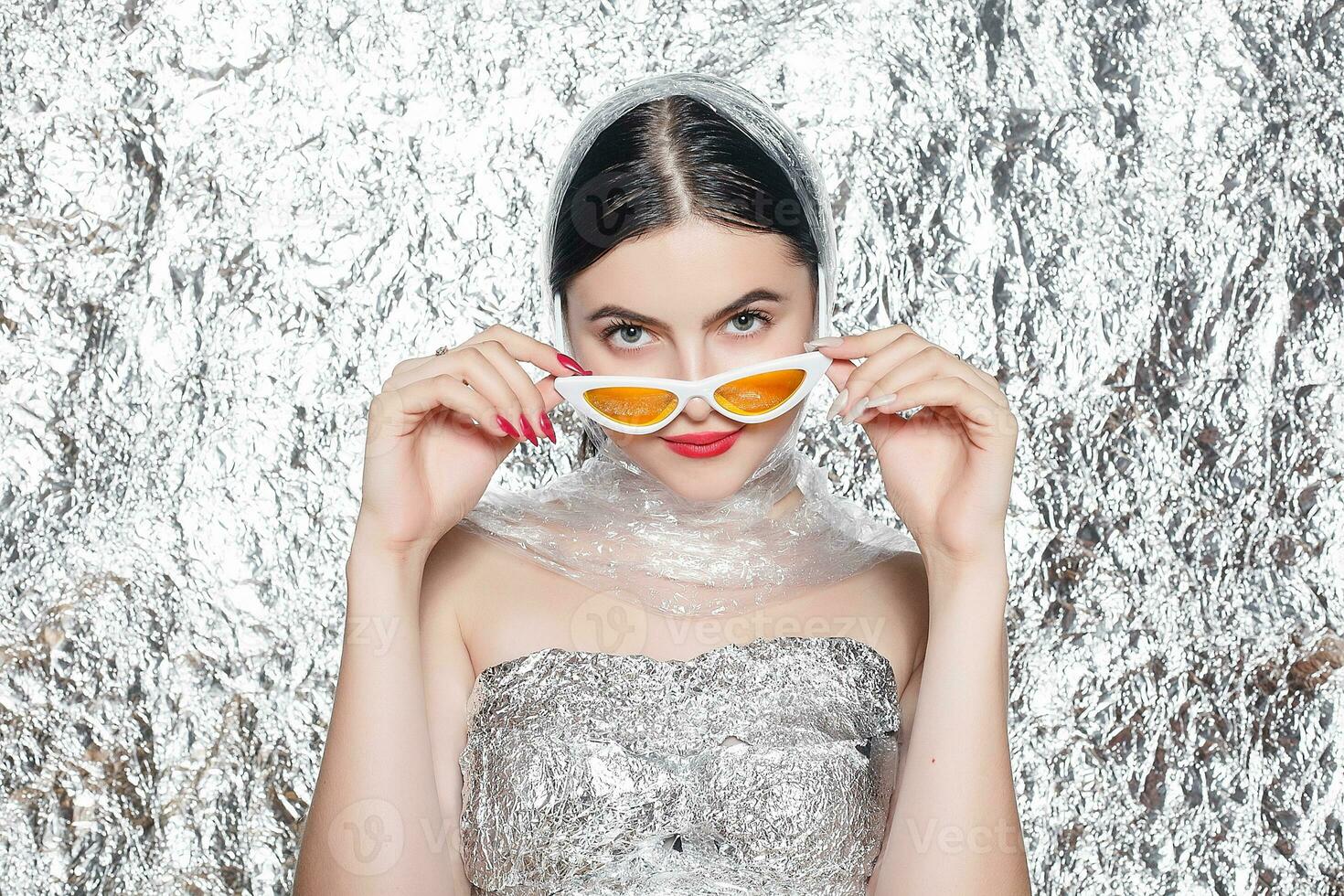 Young beautiful girl in a black dress on a silver background. photo