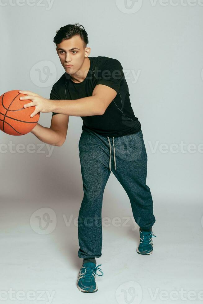 Handsome young smiling man carrying a basketball ball photo