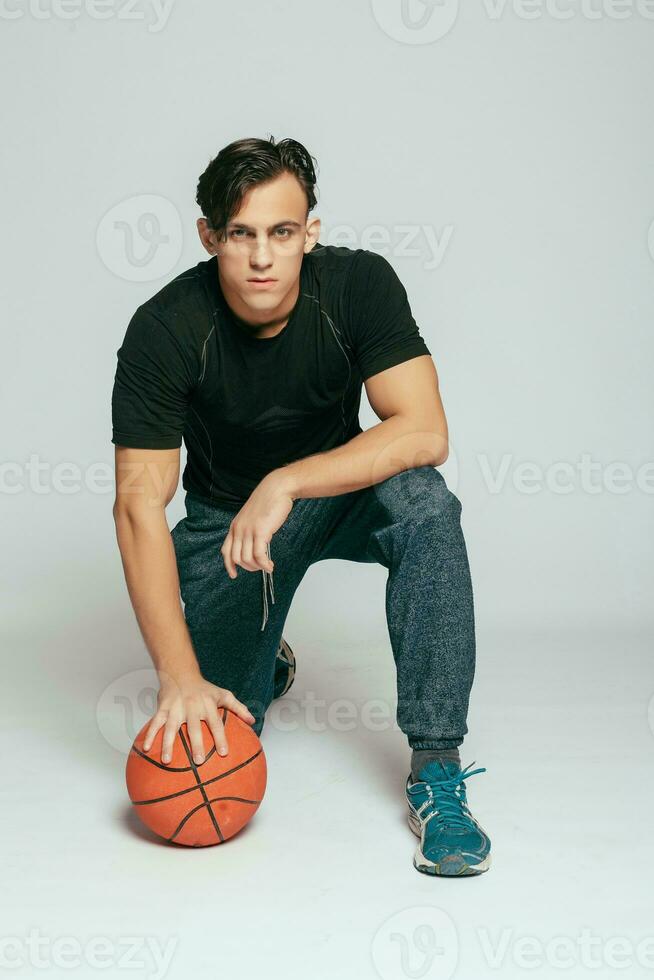 Handsome young smiling man carrying a basketball ball photo