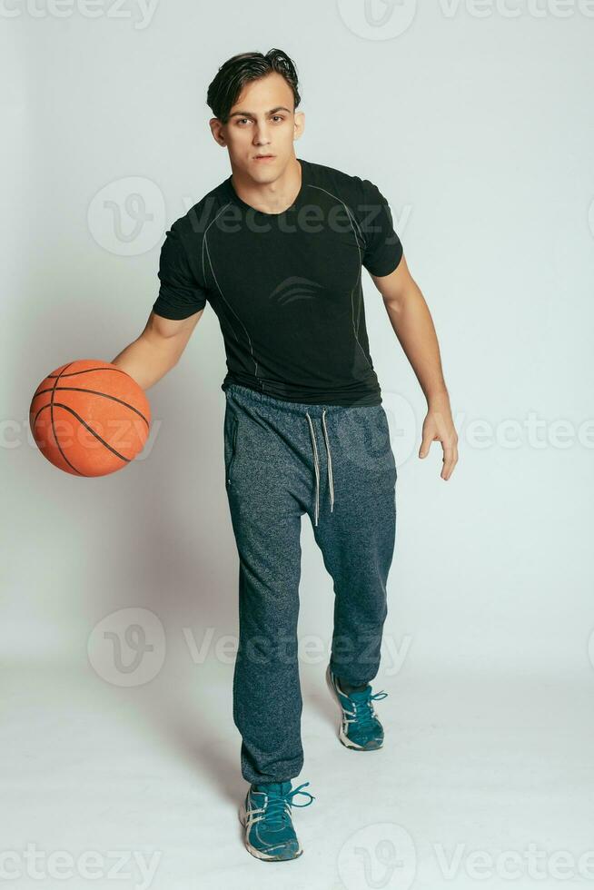 hermoso joven sonriente hombre que lleva un baloncesto pelota foto