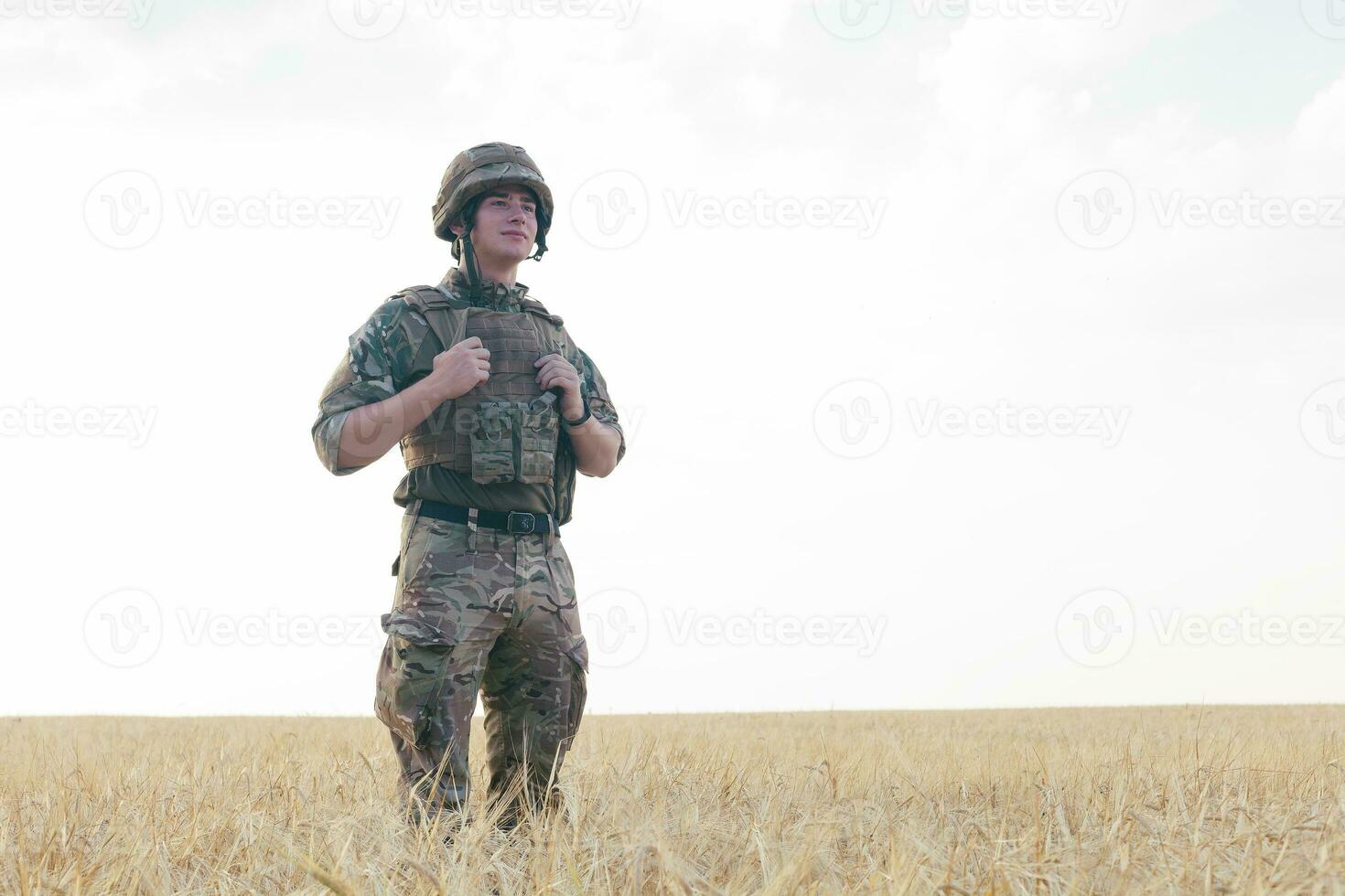 Soldier man standing against a field photo