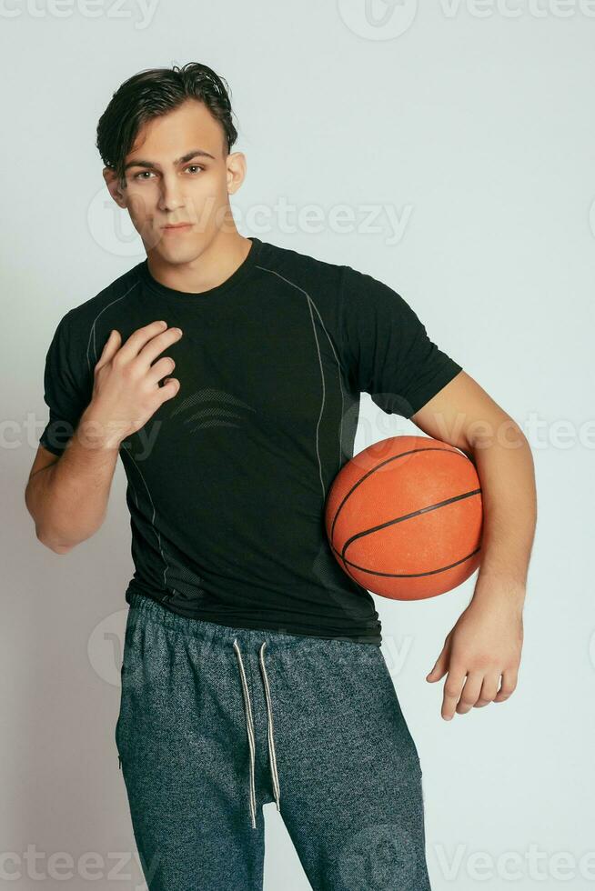 Handsome young smiling man carrying a basketball ball photo