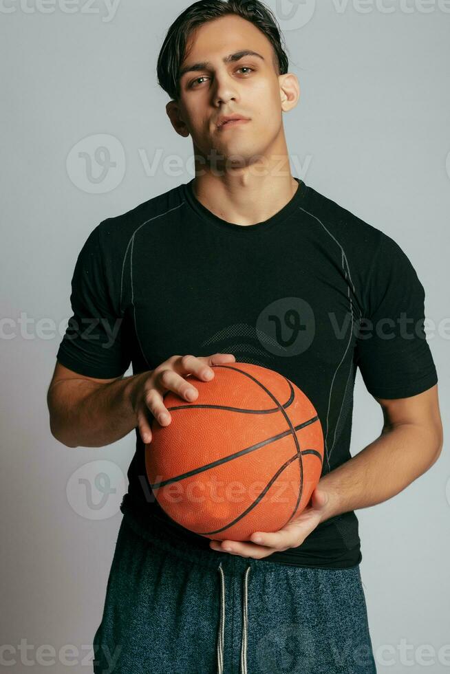 Handsome young smiling man carrying a basketball ball photo