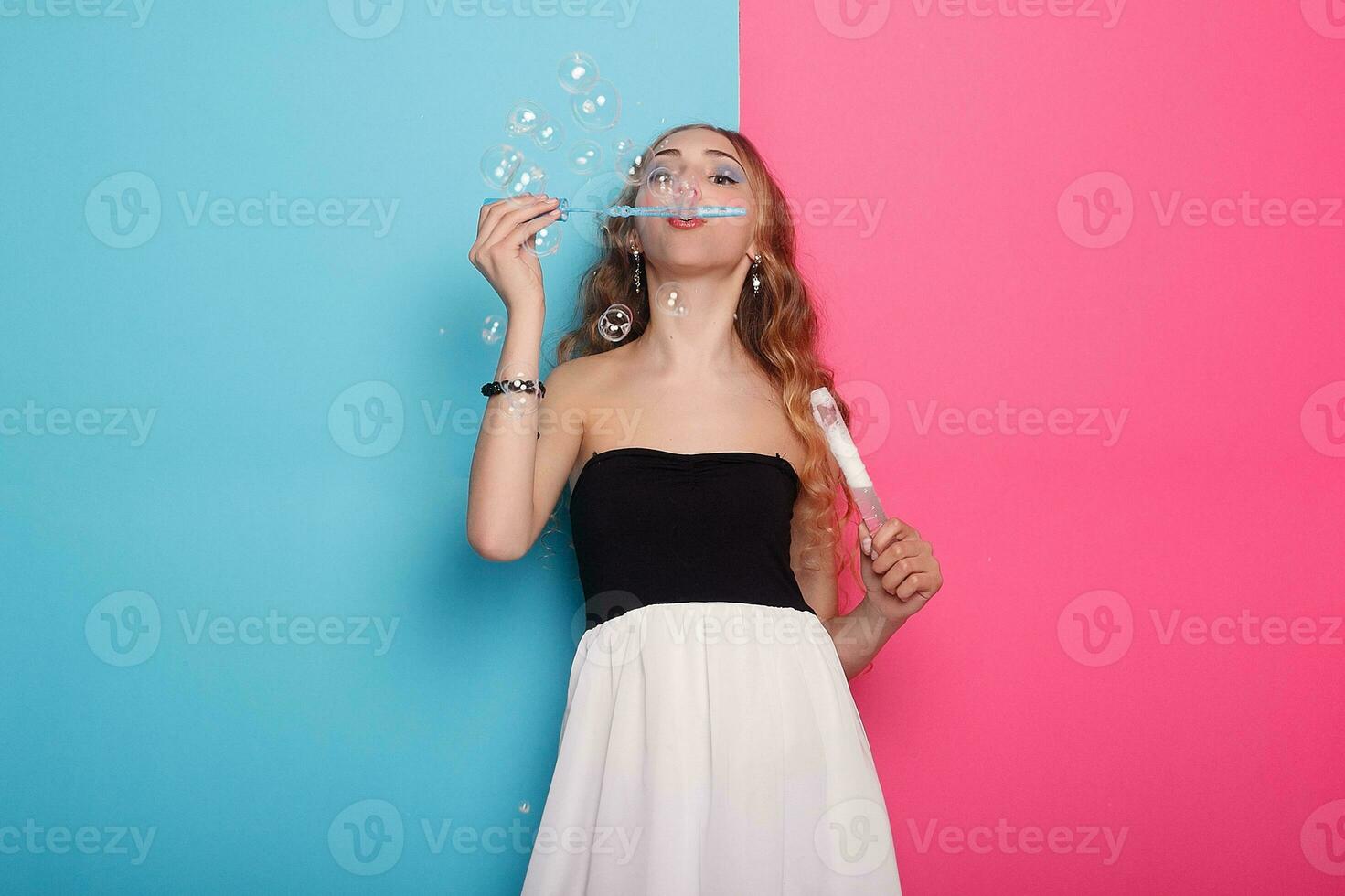 Beautiful young woman with soap bubbles over cyan background photo