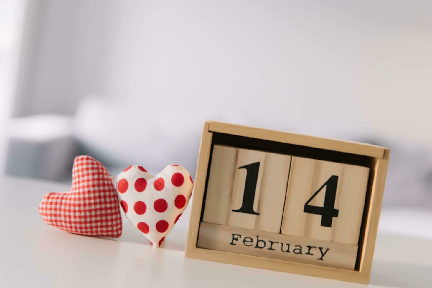 Valentines day concept. Hand make yarn red heart beside wooden block calendar set on Valentines date 14 February on table and bright room background. Happy valentine day. photo