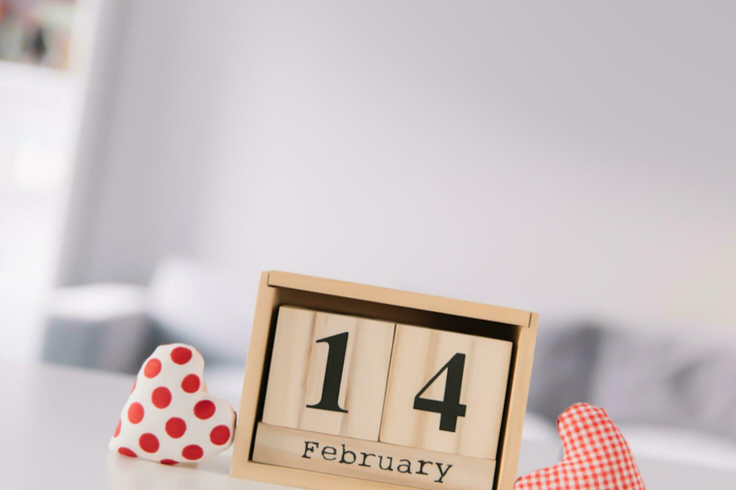 Valentines day concept. Hand make yarn red heart beside wooden block calendar set on Valentines date 14 February on table and bright room background. Happy valentine day. photo