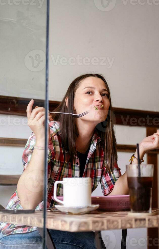 mujer haciendo gracioso cara mientras comiendo desayuno en cafetería. foto