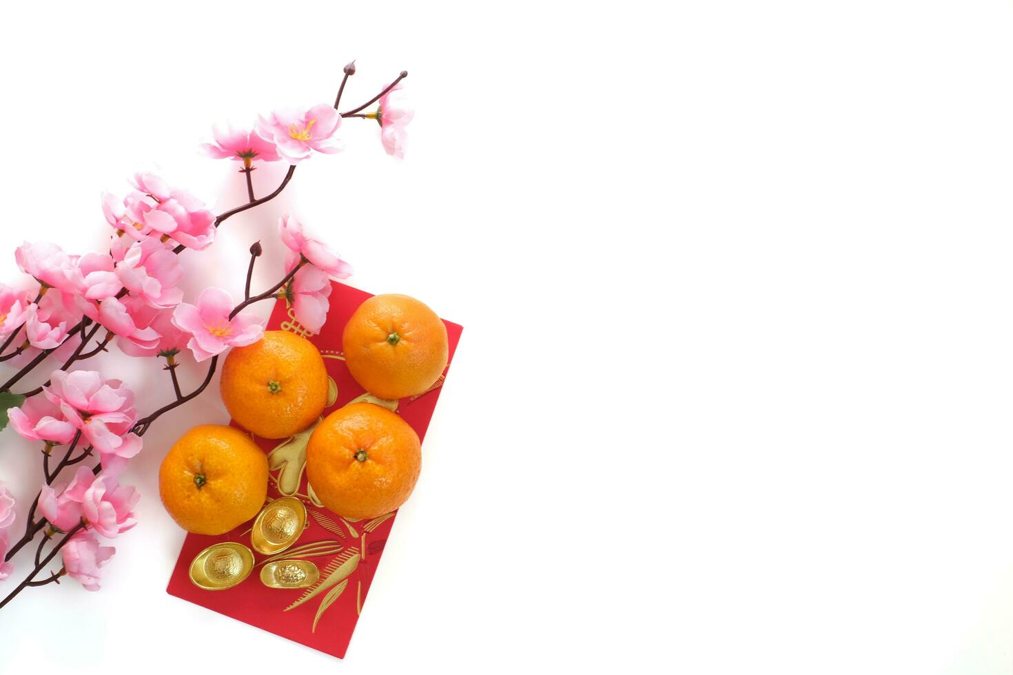 Top view of the Mandarin orange on red envelopes and gold ingot decorated with plum blossom isolated on white background. Copy space for text. Chinese New Year festival concept. photo