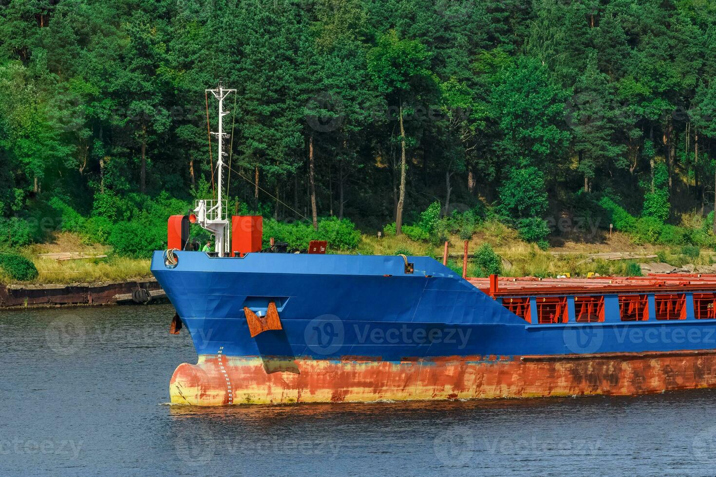 Blue cargo ship with long reach excavator moving to the port photo