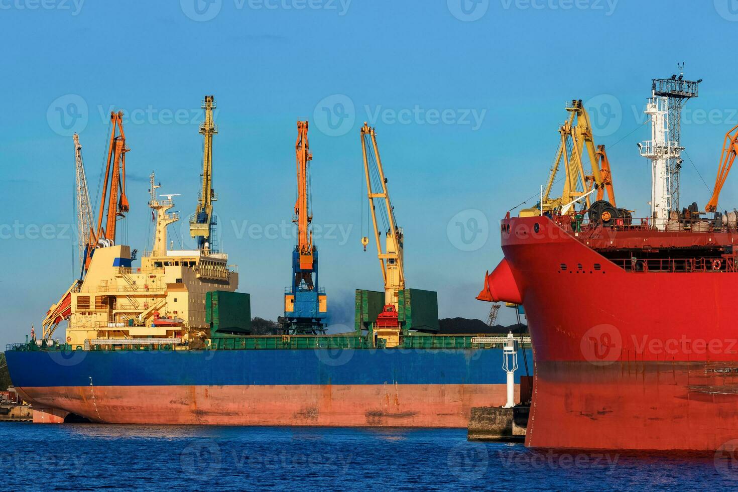 Red and blue cargo ship loading in the port of Riga photo