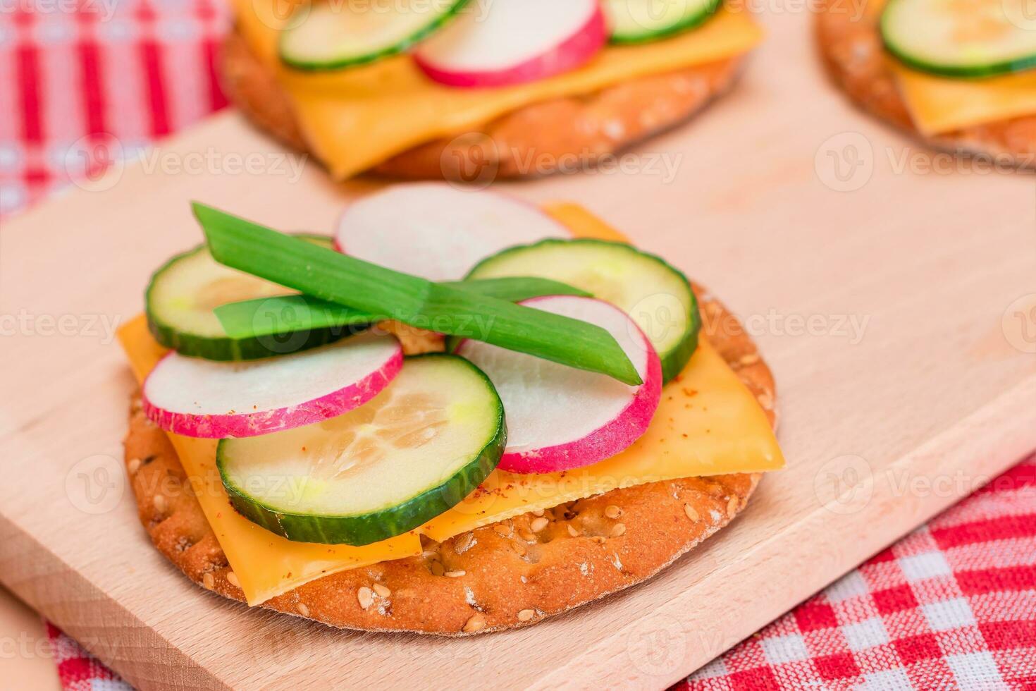 Light Breakfast. Quick and Healthy Sandwich. Fresh Cucumber and Radish with Green Onions and Cheese on Crispy Cracker on Wooden Cutting Board photo