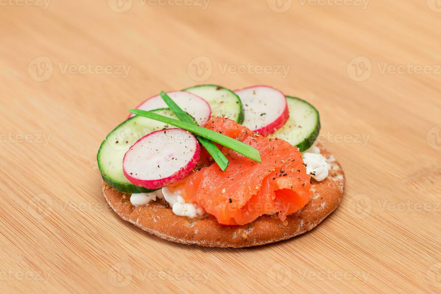 Crispy Cracker Sandwich with Salmon, Cucumber, Radish, Cottage Cheese and Green Onions on Bamboo Cutting Board. Easy Breakfast. Quick and Healthy Sandwiches. Crispbread with Tasty Filling photo
