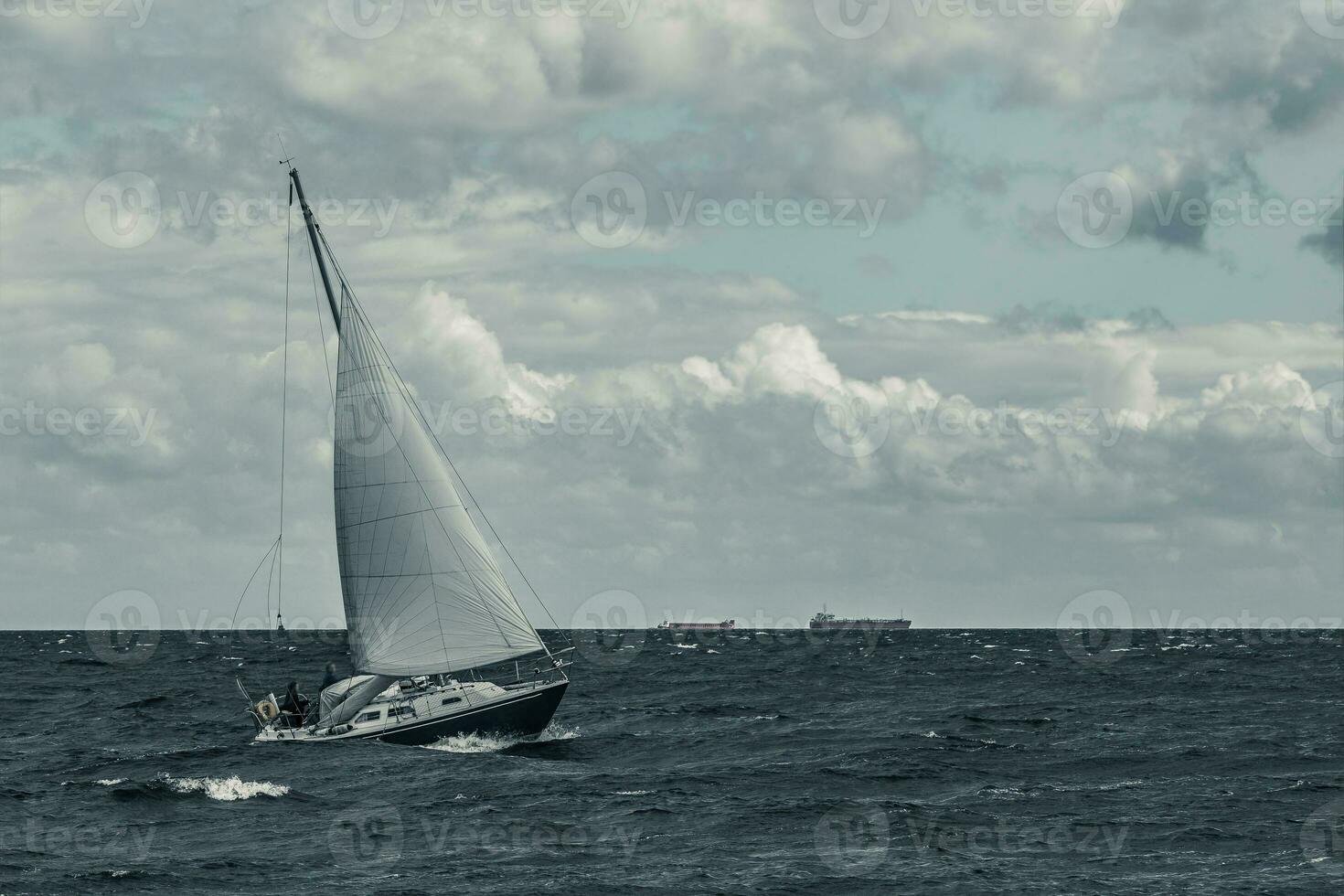 Blue sailboat in a travel at stormy sea. Regata journey. Toned photo