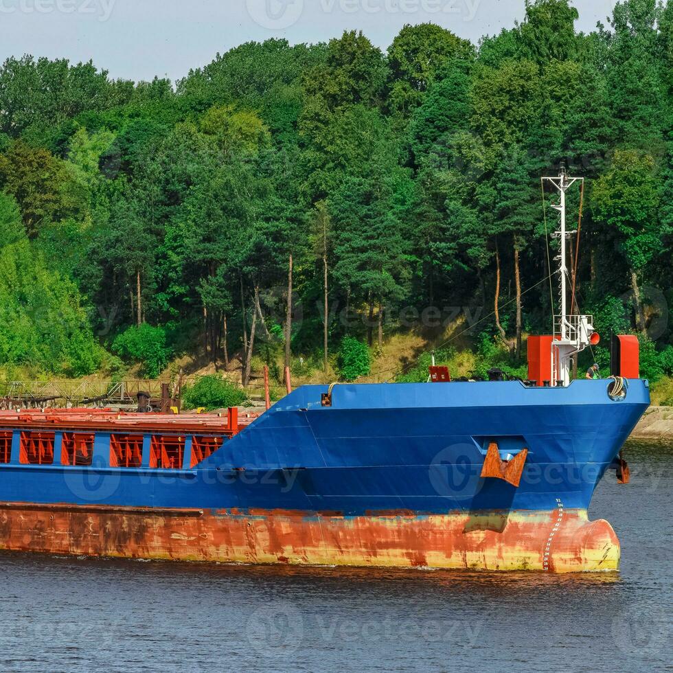 Blue cargo ship with long reach excavator moving to the port photo