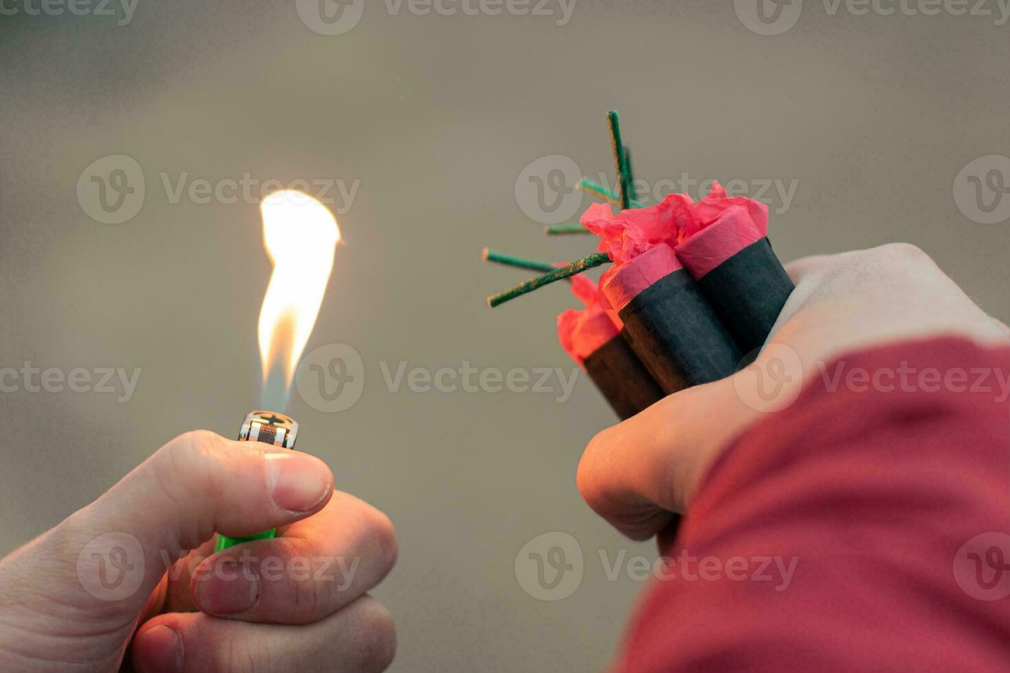 Man Lighting Up Several Firecrackers in his Hand Using Gasoline Lighter. Guy Getting Ready for New Year Fun with Fireworks or Pyrotechnic Products CloseUp Shot, Rear View photo