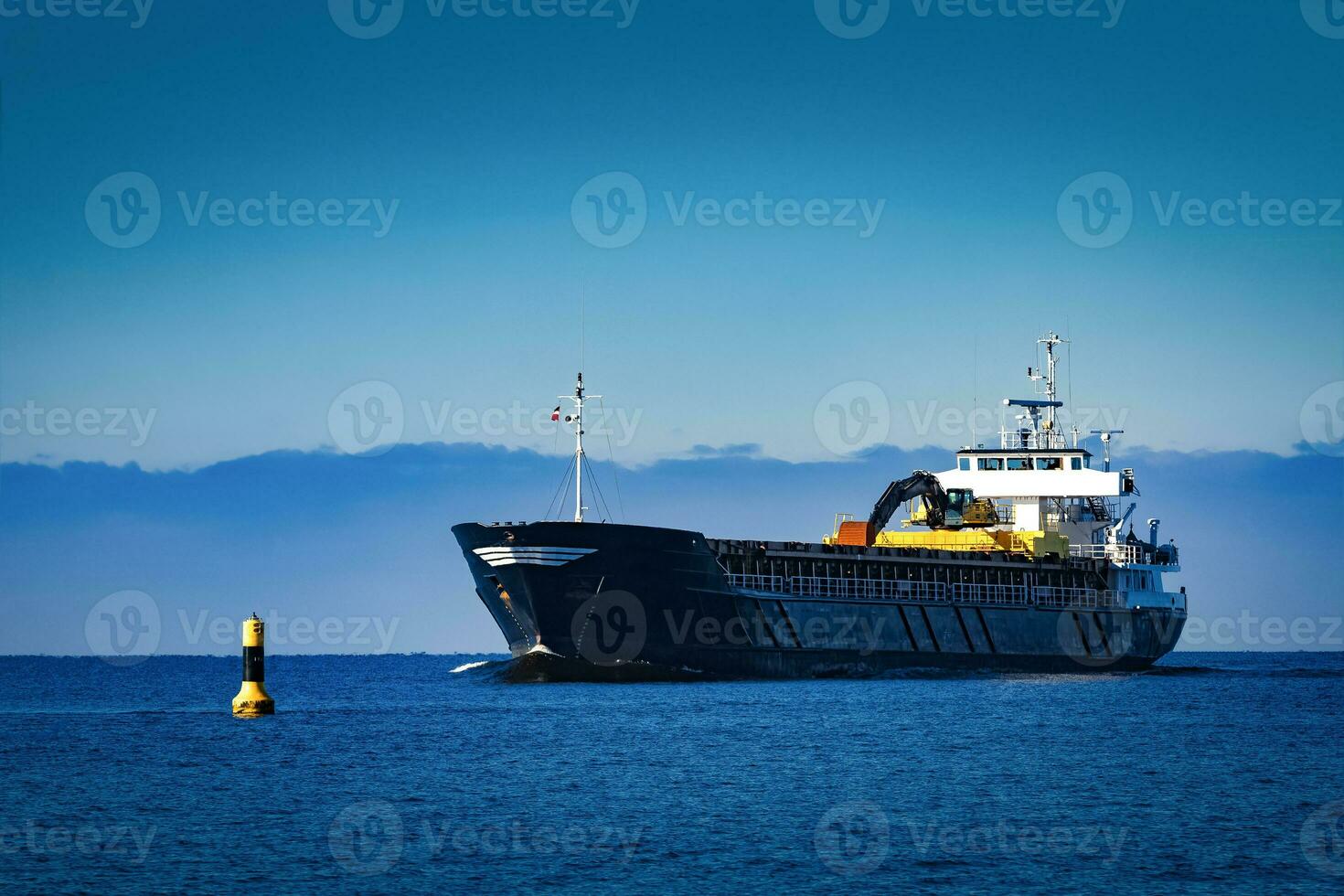 Black Sailing Bulk Carrier. Cargo Ship with Long Reach Excavator Moving in Still Water at Sunny Day by the Sea photo