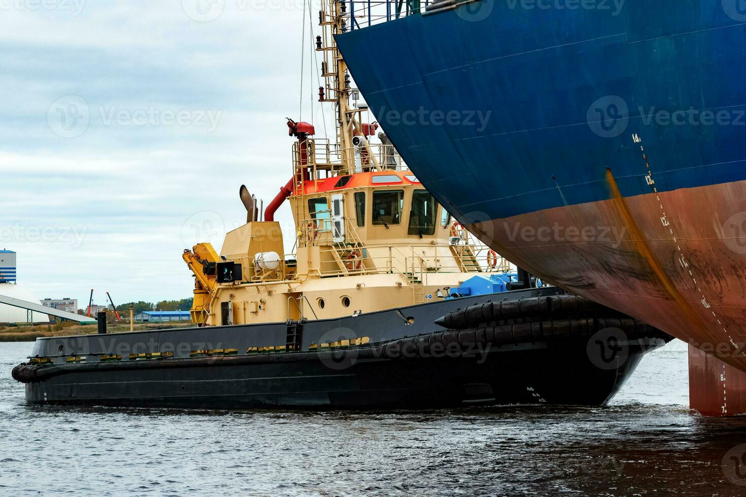 Tug ship towing blue bulk carrier in the port of Riga photo