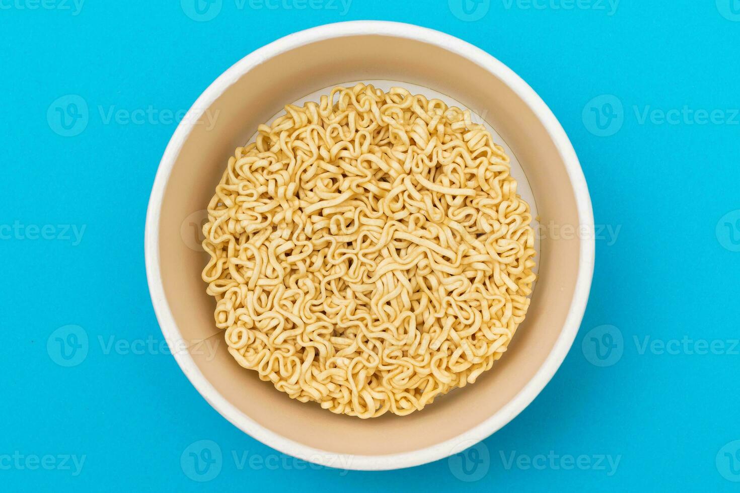 Opened Package with Uncooked Instant Noodles on Blue Background. Raw Pasta. Dry Asian Fast Food. Quick Lunch photo