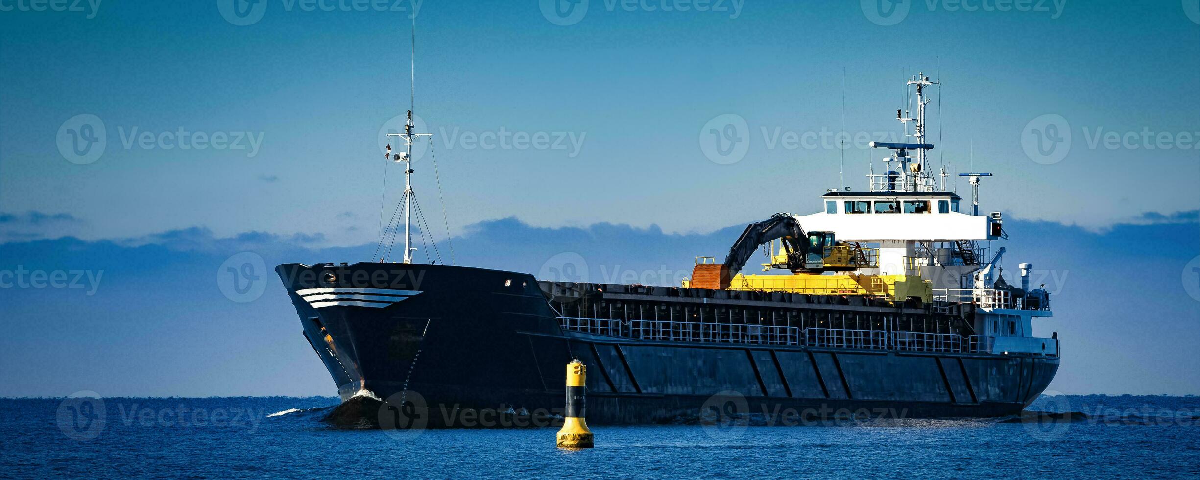 Black Sailing Bulk Carrier. Cargo Ship with Long Reach Excavator Moving in Still Water at Sunny Day by the Sea photo