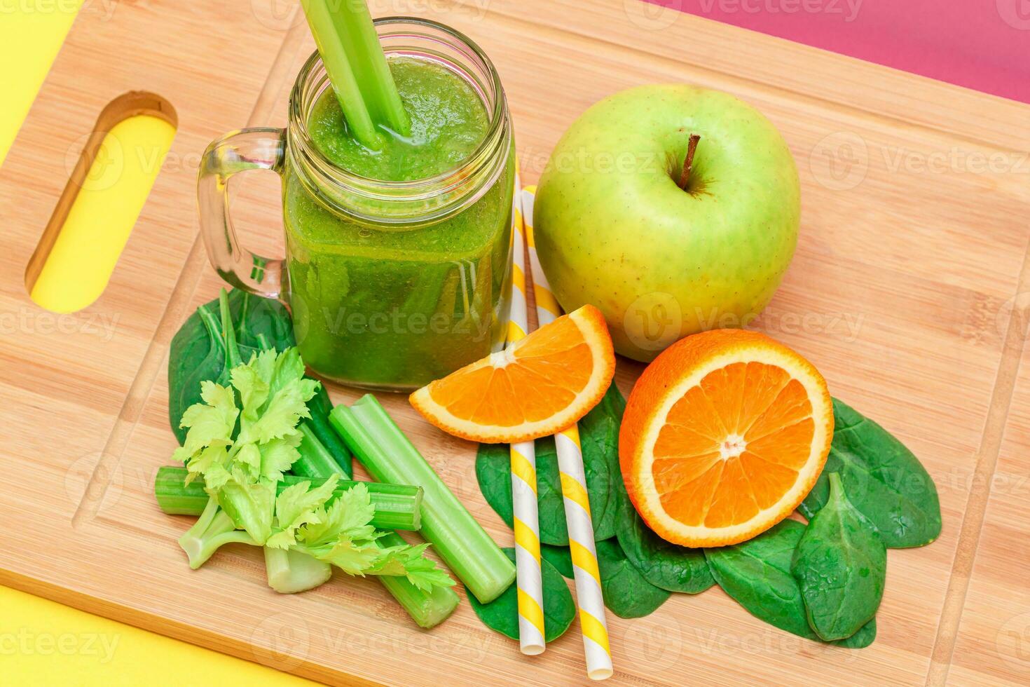 Fresco verde zalamero de manzana, apio, Espinacas y naranja en vaso zalamero tarro con amarillo cóctel Paja en de madera corte tablero. vegano desintoxicación beber. vegetariano cultura. sano comiendo y Fruta dieta foto