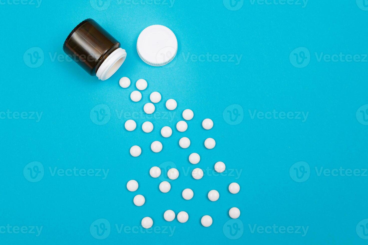 Global Pharmaceutical Industry and Medicinal Products White Pills or Tablets Scattered from the Bottle, Lying on Blue Background, Top View, Flat Lay photo