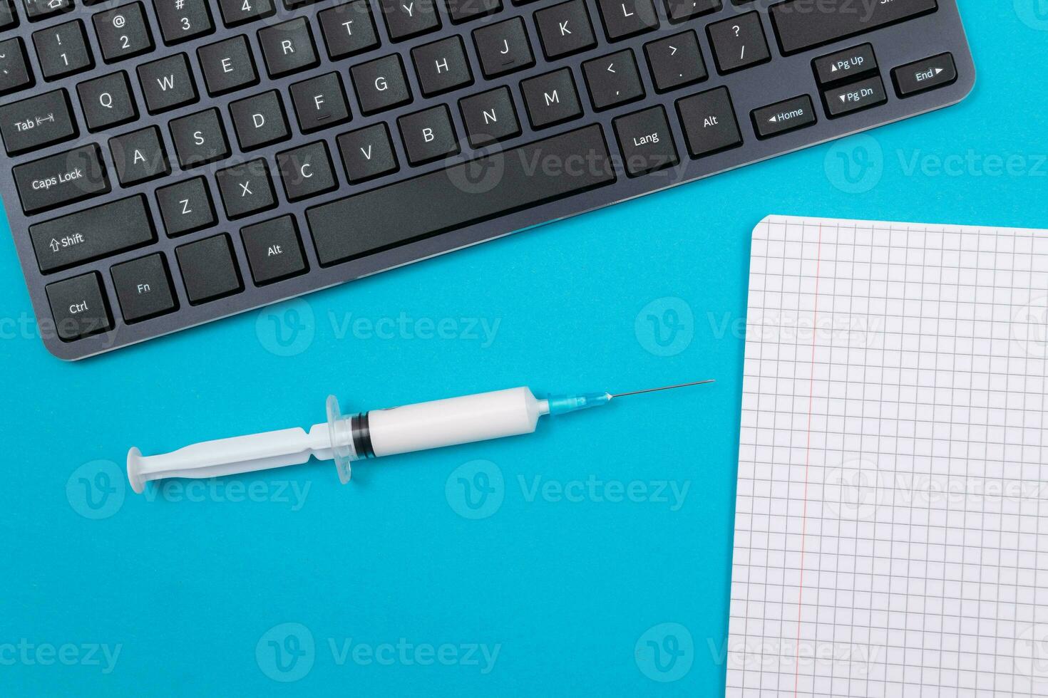 Vaccination, Immunology or Revaccination Concept A Medical Syringe Lying on Blue Table in Doctor's Office in a Hospital or Clinic. Opened Blank Notepad Mock Up with Copy Space photo